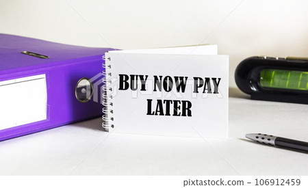 Buy now pay later concept text written on a notebook and a white background, next to a folder Buy now pay later concept text written on a notebook and a white background, next to a folder 106912459