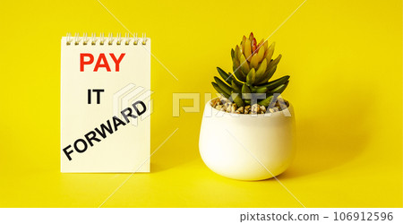 The phrase Pay It Forward with text on a white notepad, placed on a yellow background, 106912596