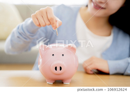 A woman who puts money in a piggy bank A woman who puts money in a piggy bank 106912624