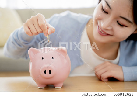A woman who puts money in a piggy bank A woman who puts money in a piggy bank 106912625