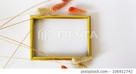Layout with a gold border and dry flowers on a white background. Layout of the top view. Layout with a gold border and dry flowers on a white background. Layout of the top view. 106912742