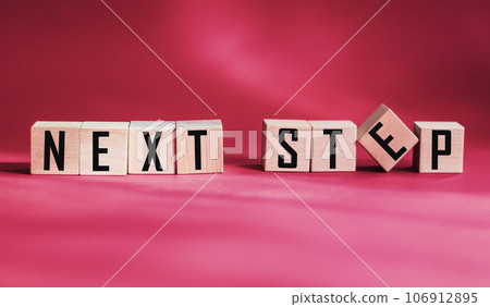 Words NEXT STEP on wooden cubes on red background, close-up shot Words NEXT STEP on wooden cubes on red background, close-up shot 106912895
