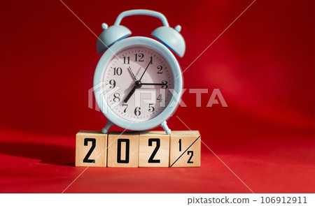 Wooden cubes modified from 2021 to 2022 with clock. Red background with copy space. Wooden cubes modified from 2021 to 2022 with clock. Red background with copy space. 106912911