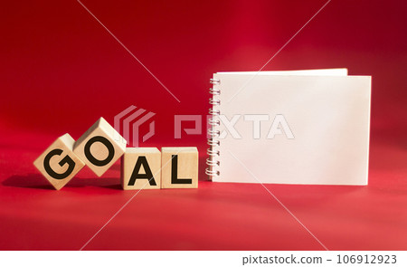 Goal word made from building blocks isolated on red background with notepad for writing 106912923