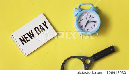 Text New day on notepad, start symbol. Beautiful yellow background. Copy space.  106912980