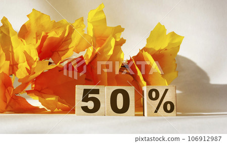 50 percent written on wooden blocks against orange foliage background and white backdrop 106912987