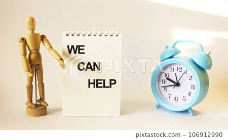 We can help, text on a notebook and a wooden doll and a clock on a white background We can help, text on a notebook and a wooden doll and a clock on a white background 106912990