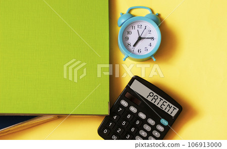 PATENT text written on the display of a calculator on a yellow background with a folder PATENT text written on the display of a calculator on a yellow background with a folder 106913000