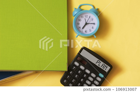 Word plan on a calculator on a yellow background with a folder for documents and a clock 106913007