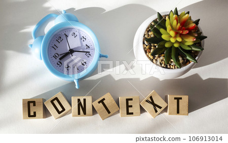Context word in wooden cube with alarm clock and cactus flower on white background Context word in wooden cube with alarm clock and cactus flower on white background 106913014
