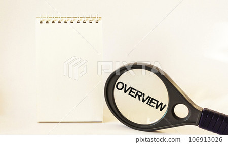 Overview, the text is written on a magnifying glass next to a notepad. White background Overview, the text is written on a magnifying glass next to a notepad. White background 106913026