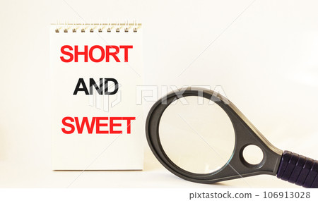 Short and sweet, written on notepad and white background. Near a magnifying glass Short and sweet, written on notepad and white background. Near a magnifying glass 106913028