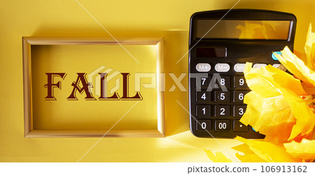 Autumn text on golden frame and autumn leaves with calculator on yellow background 106913162