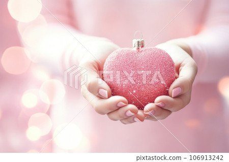 Christmas heart shaped decoration in woman's hands on pink background Christmas heart shaped decoration in woman's hands on pink background 106913242