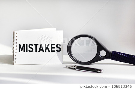 MISTAKES- word on notepad and white background, pen, magnifier near. Business concept MISTAKES- word on notepad and white background, pen, magnifier near. Business concept 106913346
