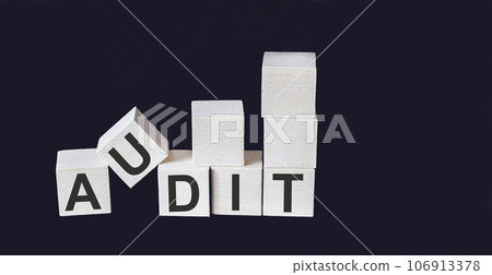 AUDIT word written on wooden block and black background 106913378