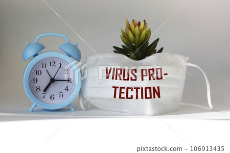 text VIRUS PROTECTION on medical mask and light background. Cactus and clock. Medical concept. text VIRUS PROTECTION on medical mask and light background. Cactus and clock. Medical concept. 106913435