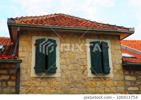 The old window with green closed shutters on an old house. Vintage texture. Herceg Novi, Montenegro, old stone house. Architecture of the Adriatic region. Fixing windows and shutters to the wall The old window with green closed shutters on an old house. Vintage texture. Herceg Novi, Montenegro, old stone house. Architecture of the Adriatic region. Fixing windows and shutters to the wall 106913754