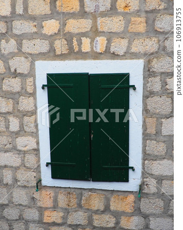 The old window with green closed shutters on an old house. Vintage texture. Herceg Novi, Montenegro, old stone house. Architecture of the Adriatic region. Fixing windows and shutters to the wall The old window with green closed shutters on an old house. Vintage texture. Herceg Novi, Montenegro, old stone house. Architecture of the Adriatic region. Fixing windows and shutters to the wall 106913755