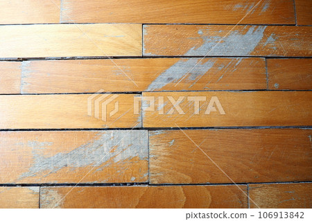 Old, scratched parquet flooring needs maintenance. The parquet is damaged by scratches from prolonged use. 106913842