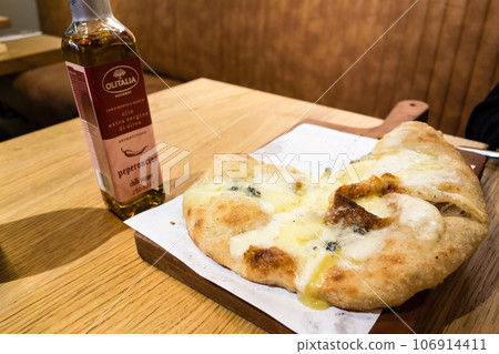 倫敦一家意大利餐廳桌上的 Calzone 和一瓶辣椒油 倫敦一家意大利餐廳桌上的 Calzone 和一瓶辣椒油 106914411