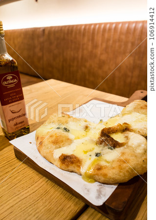 倫敦一家意大利餐廳桌上的 Calzone 和一瓶辣椒油 倫敦一家意大利餐廳桌上的 Calzone 和一瓶辣椒油 106914412
