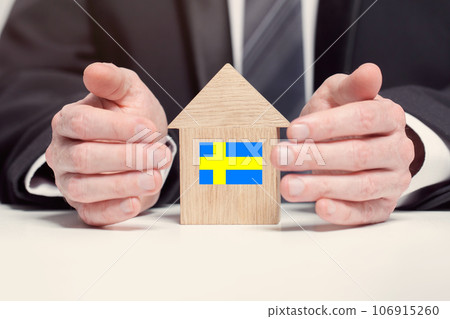 Businessman hand holding wooden home model with Swedish flag. insurance and property concepts Businessman hand holding wooden home model with Swedish flag. insurance and property concepts 106915260