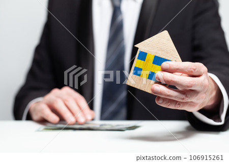 Businessman hand holding wooden home model with Swedish flag. insurance and property concepts Businessman hand holding wooden home model with Swedish flag. insurance and property concepts 106915261