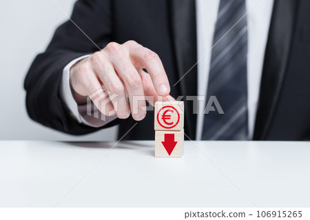 Wooden blocks with red currency euro icon and red arrow down. Growth and depreciation concept. Wooden blocks with red currency euro icon and red arrow down. Growth and depreciation concept. 106915265