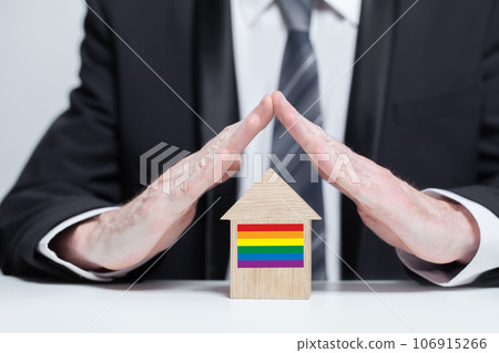 Businessman protecting wooden house with LGBT flag on it Businessman protecting wooden house with LGBT flag on it 106915266