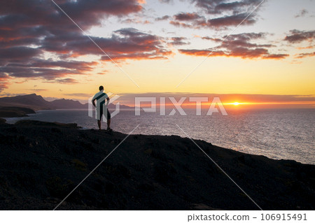 Man looks at the evening over the sea and the bright shining sunset on the Canary Islands in the evening light 106915491