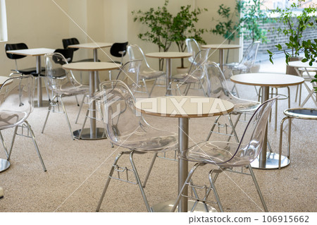 Seating inside the cafe or restaurant, with transparent chairs and white tables. 106915662