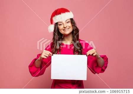 Beautiful Christmas woman in Santa hat holding blank empty paper banner board 106915715