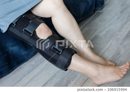 Woman in knee brace support for leg or knee injury at home, leg close up 106915994
