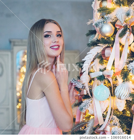 Cute cheerful smiling blonde model woman with Christmas tree at home. Cute cheerful smiling blonde model woman with Christmas tree at home. 106916014
