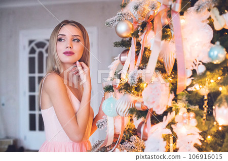 Christmas portrait of happy blonde woman with Xmas tree at home Christmas portrait of happy blonde woman with Xmas tree at home 106916015