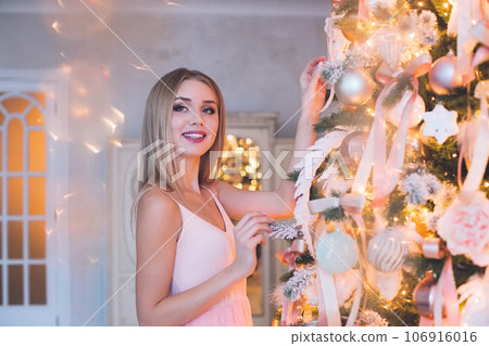 Gorgeous smiling blonde woman standing near Christmas tree at home. Gorgeous smiling blonde woman standing near Christmas tree at home. 106916016