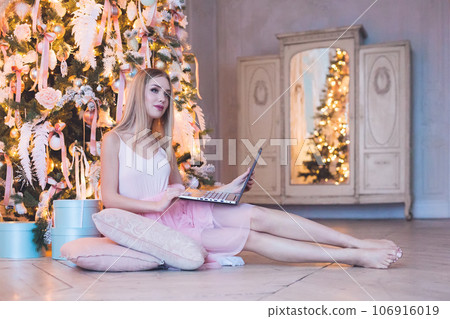 Young beautiful woman sitting using laptop at home. Christmas and New Year holidays concept Young beautiful woman sitting using laptop at home. Christmas and New Year holidays concept 106916019