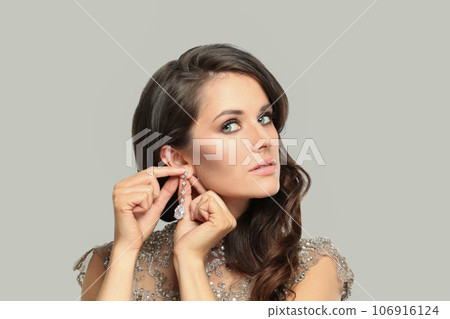 Jewelry model woman in long diamond earring on white. Beautiful woman brunette Jewelry model woman in long diamond earring on white. Beautiful woman brunette 106916124