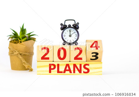 2024 plans new year symbol. Businessman turns a wooden cube and changes words Plans 2023 to Plans 2024. Beautiful white table white background, copy space. Business 2024 plans new year concept. 2024 plans new year symbol. Businessman turns a wooden cube and changes words Plans 2023 to Plans 2024. Beautiful white table white background, copy space. Business 2024 plans new year concept. 106916834