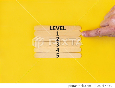 Time to level 1 symbol. Concept word Level 1 2 3 4 5 on wooden sticks. Businessman hand. Beautiful yellow table yellow background. Business planning and time to level 1 concept. Copy space. 106916859