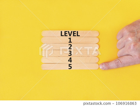 Time to level 5 symbol. Concept word Level 1 2 3 4 5 on wooden sticks. Businessman hand. Beautiful yellow table yellow background. Business planning and time to level 5 concept. Copy space. 106916863