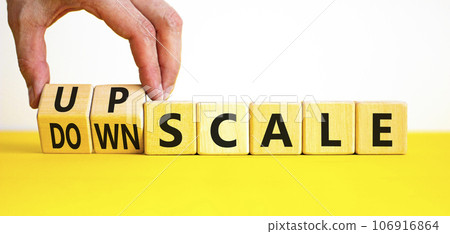 Upscale or downscale symbol. Concept words Upscale or Downscale on wooden cubes. Beautiful yellow table white background. Businessman hand. Business upscale or downscale concept. Copy space. 106916864