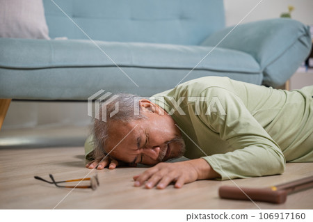 Elder man falling on the floor alone with walking stick on living room at home, Older senior man headache lying on the floor after falling down, Health care and medicine concept 106917160