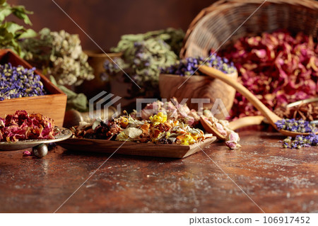 Various dried medicinal plants on a brown background. 106917452