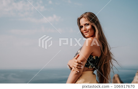 Woman travel sea. Happy tourist taking picture outdoors for memories. Woman traveler looks at the edge of the cliff on the sea bay of mountains, sharing travel adventure journey Woman travel sea. Happy tourist taking picture outdoors for memories. Woman traveler looks at the edge of the cliff on the sea bay of mountains, sharing travel adventure journey 106917670