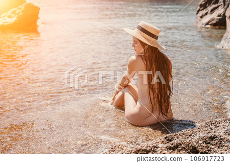 Woman travel sea. Happy tourist in hat enjoy taking picture outdoors for memories. Woman traveler posing on the beach at sea surrounded by volcanic mountains, sharing travel adventure journey Woman travel sea. Happy tourist in hat enjoy taking picture outdoors for memories. Woman traveler posing on the beach at sea surrounded by volcanic mountains, sharing travel adventure journey 106917723