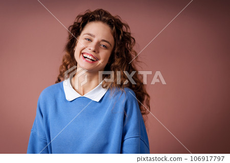 Happy smiling young adult woman wearing winter blue sweater indoors looking at camera with joyful smile Happy smiling young adult woman wearing winter blue sweater indoors looking at camera with joyful smile 106917797
