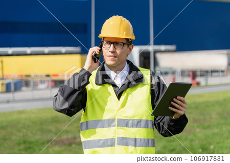 Logistician with phone and digital tablet on a background of logistic center. 106917881
