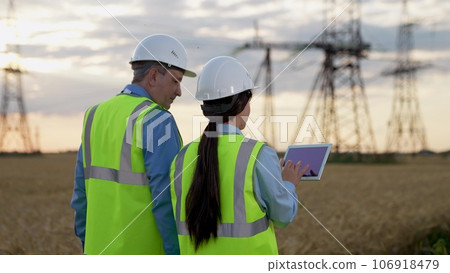 Skilled engineer inspects work of power distribution substation with electrician 106918479